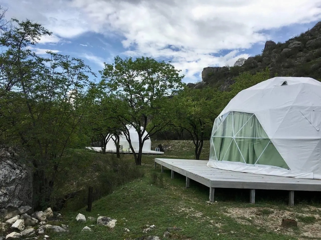 Сферические купольные глэмпинги на деревянных помостах среди деревьев
